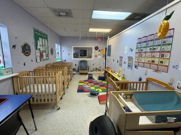 Infant room with cribs, a changing station, and colorful wall charts