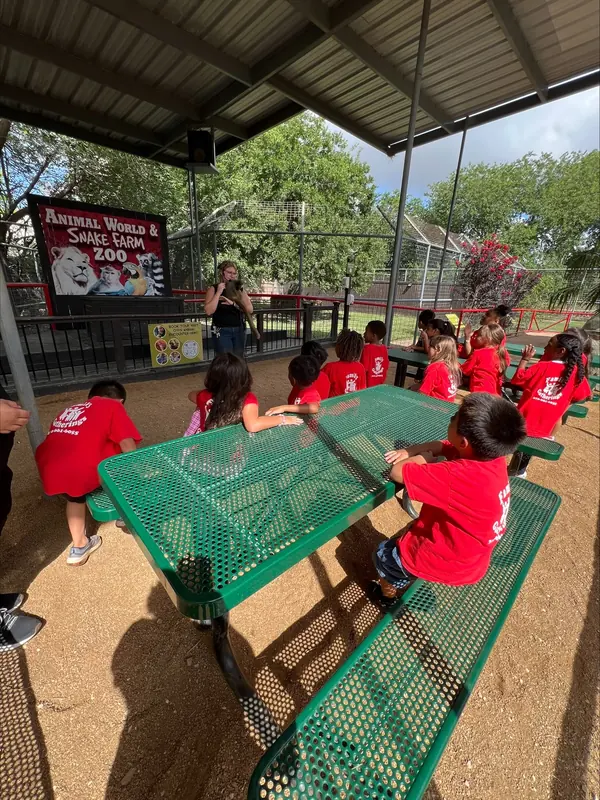 Summer campers under a shaded pavilion on a zoo field trip