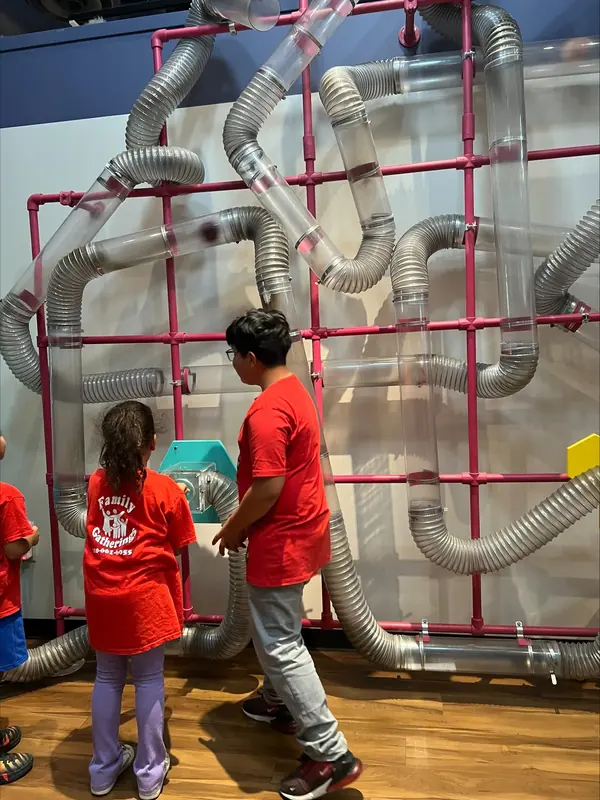 Summer campers watching a ball-run exhibit at a children's museum